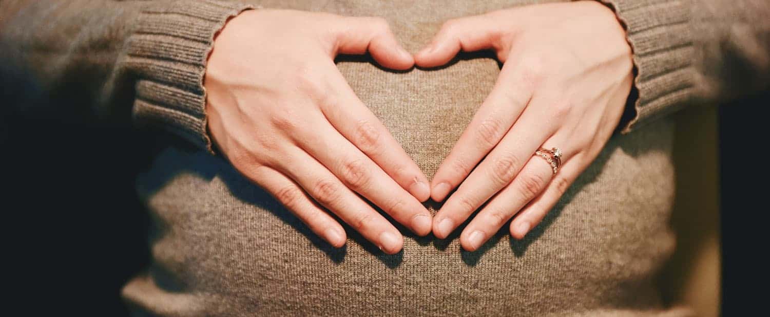 Pregnant woman making a heart with her hand 