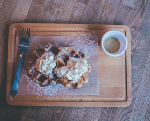 a wooden plate with 2 waffles placed on top