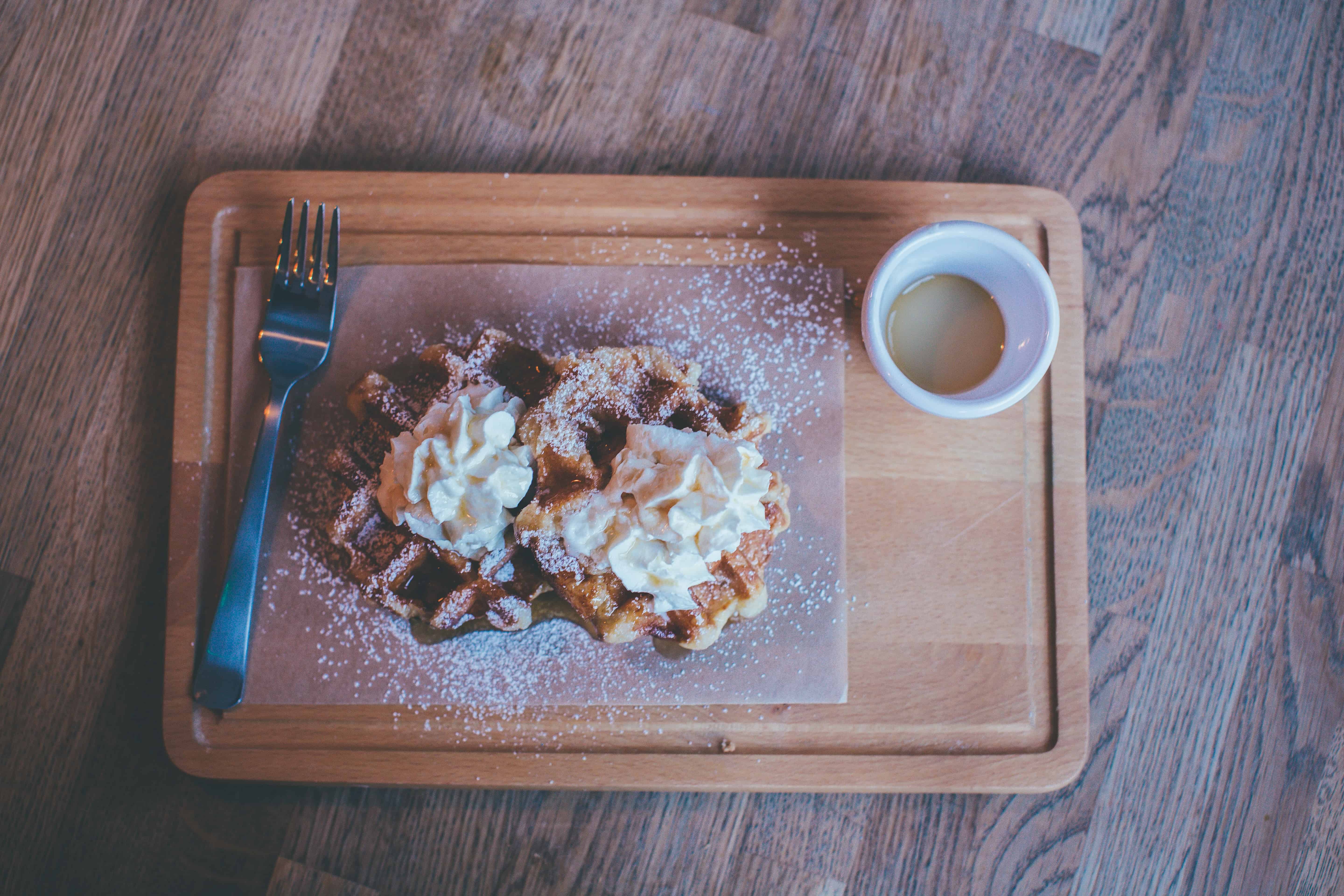 a wooden plate with 2 waffles placed on top